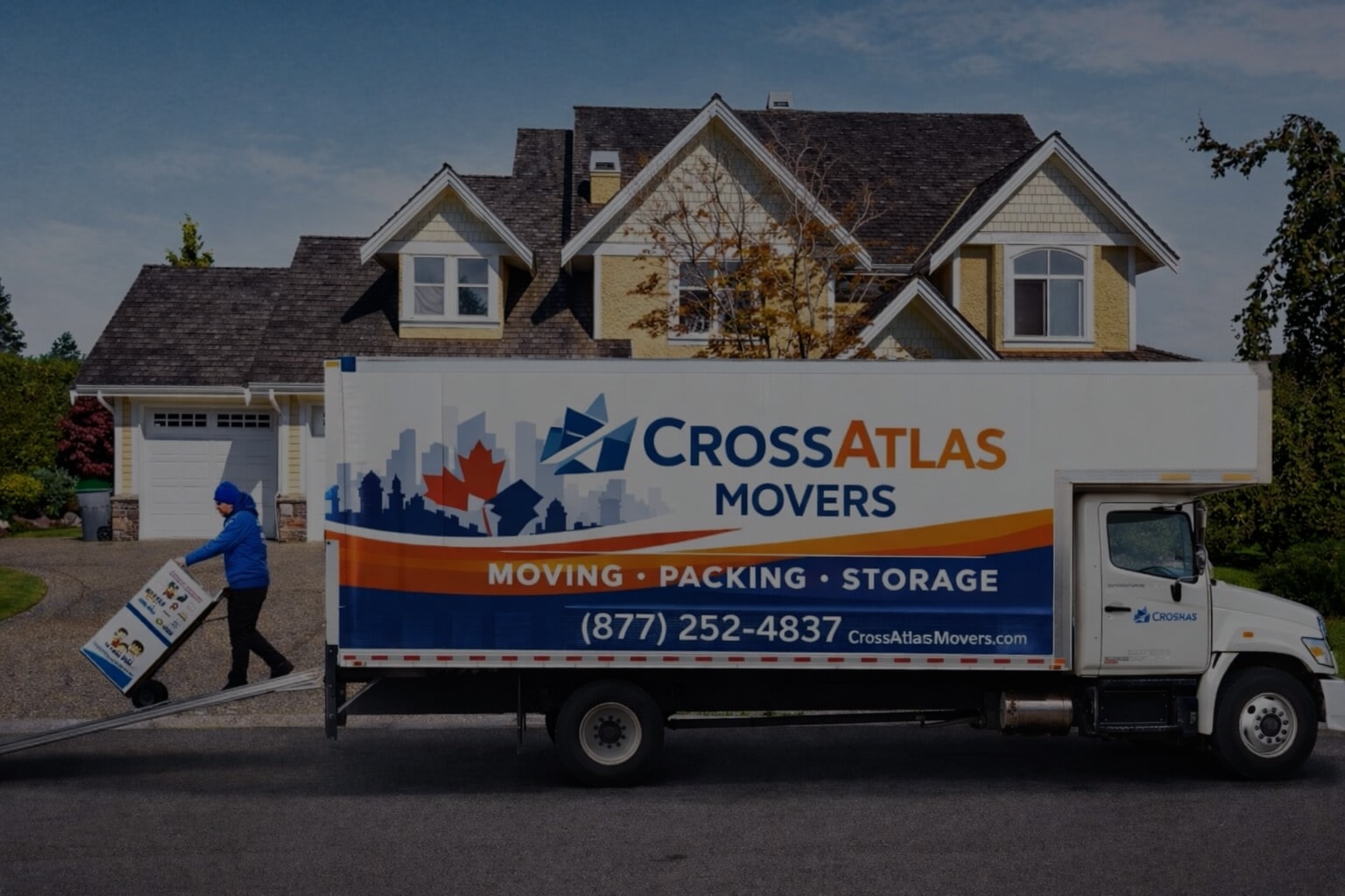 CrossAtlas Movers truck and mover unloading boxes at a house during a long-distance move with Vancouver to Salmon Arm movers.
